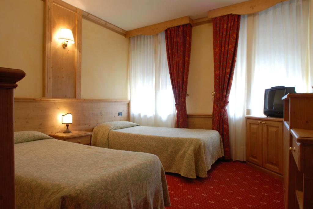 um quarto de hotel com duas camas e uma televisão em Hotel Alpi - Foza em Foza