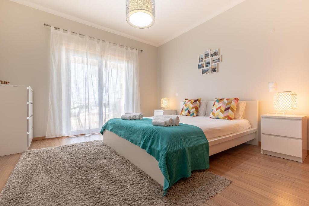 um quarto com uma cama e uma grande janela em Apartamento 7 Mares com Suite em Sagres