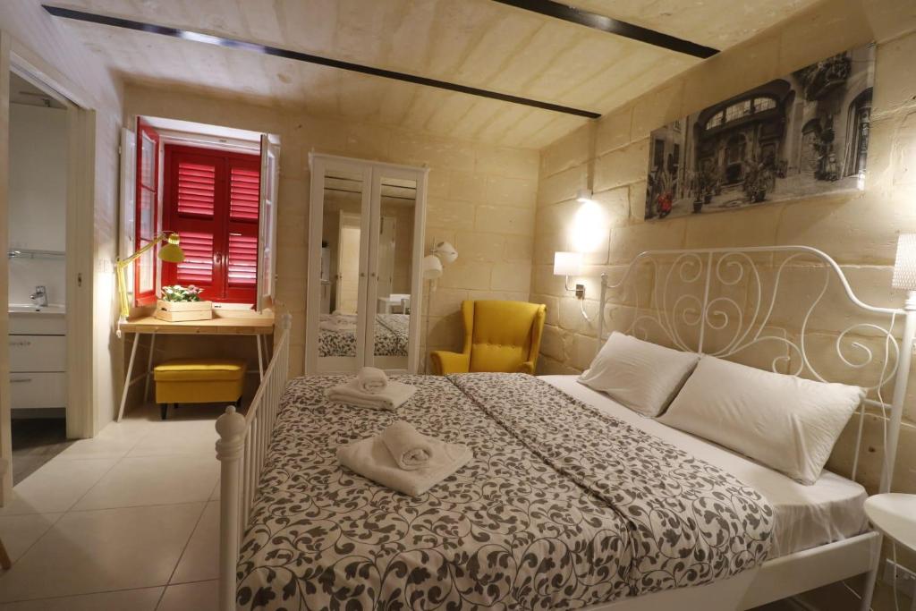 um quarto com uma cama, uma secretária e uma janela em Valletta Central Suites em Valeta