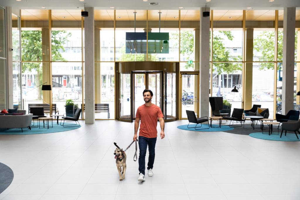 a man walking a dog in a lobby at Holiday Inn Express Amsterdam - North Riverside by IHG in Amsterdam