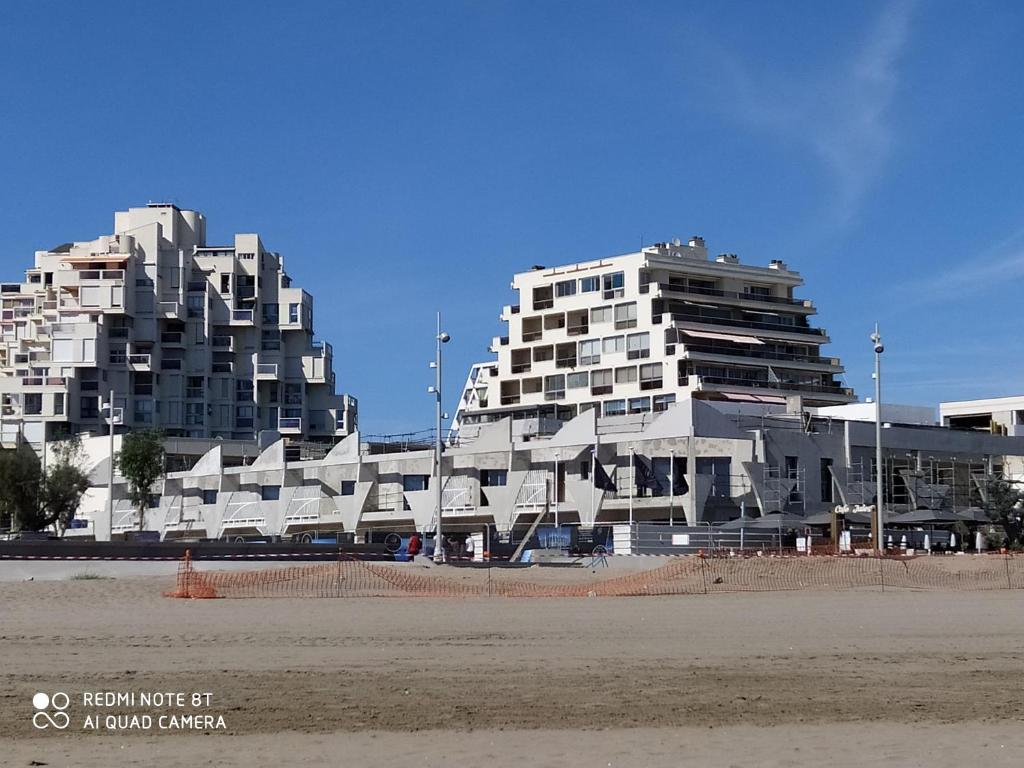 2 grands bâtiments sur une plage avec une plage dans l'établissement L'Acapulco, à La Grande Motte