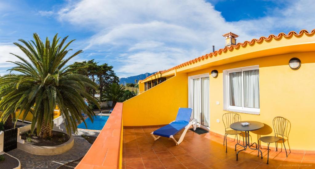 a yellow house with a patio with a table and chairs at Apartamentos Villa María in Los Llanos de Aridane