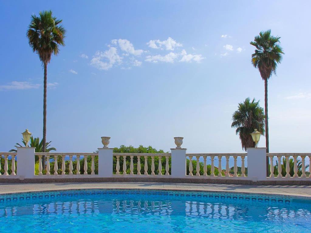 uma piscina com cerca e palmeiras em Casa de la Belvedere - Wonderful sea views - Elegant terrace area - Great for families em Son Bou