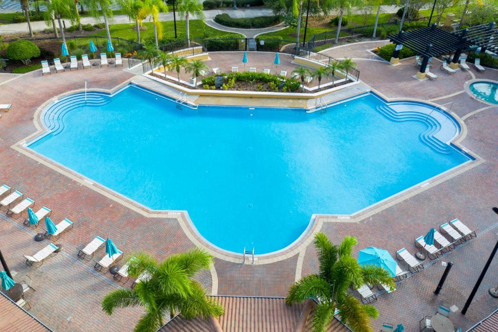 una vista sul tetto di una grande piscina con sedie e palme di Magnificent 2 Bedroom Apartment Vista Cay Resort 107 a Orlando