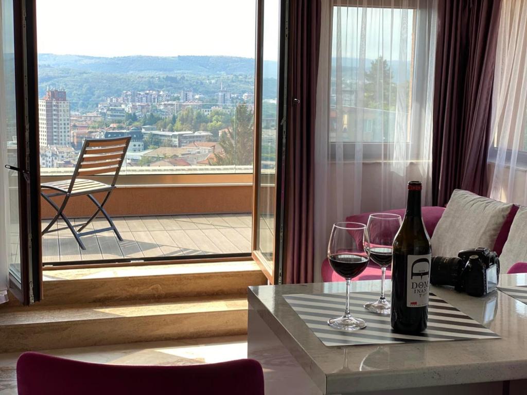 ヴェリコ・タルノヴォにあるAmazing view and cozy atmosphereのワイングラス付きのテーブルに座ったワイン1本