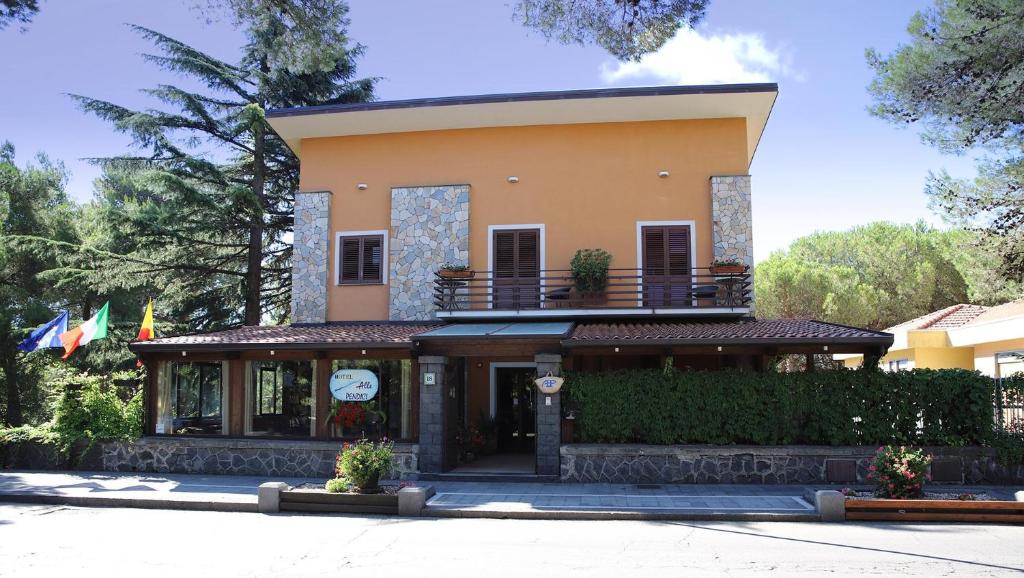 un grand bâtiment jaune avec un balcon au-dessus dans l'établissement Hotel Alle Pendici, à Nicolosi