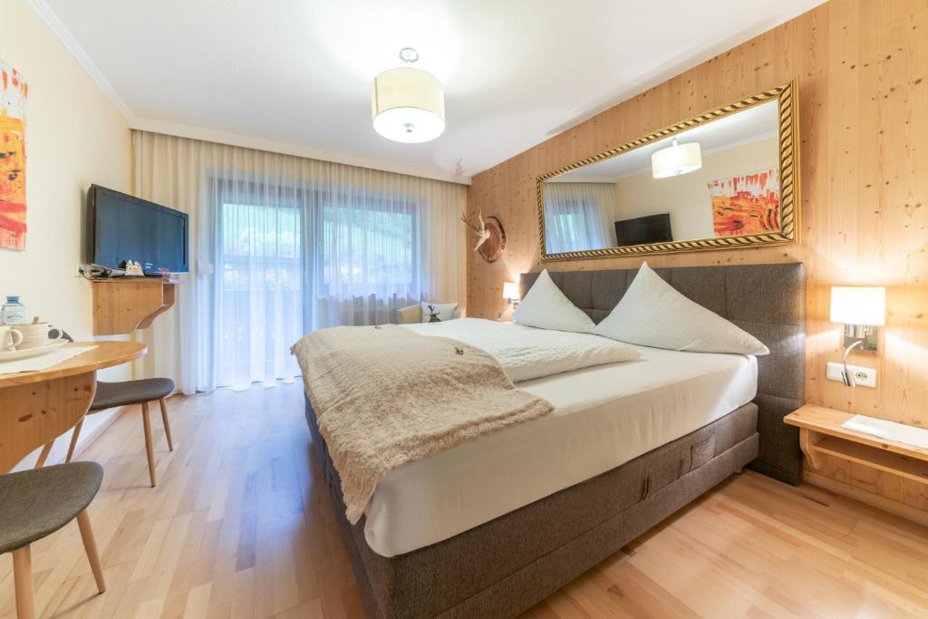 1 dormitorio con 1 cama grande y espejo en Gästehaus Brugger Martin, en Sölden