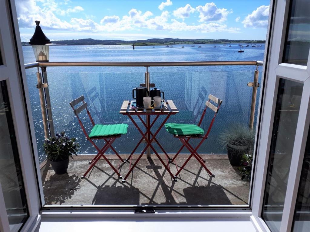 a table and chairs on a balcony with a view of the water at Rock Quay in Killyleagh