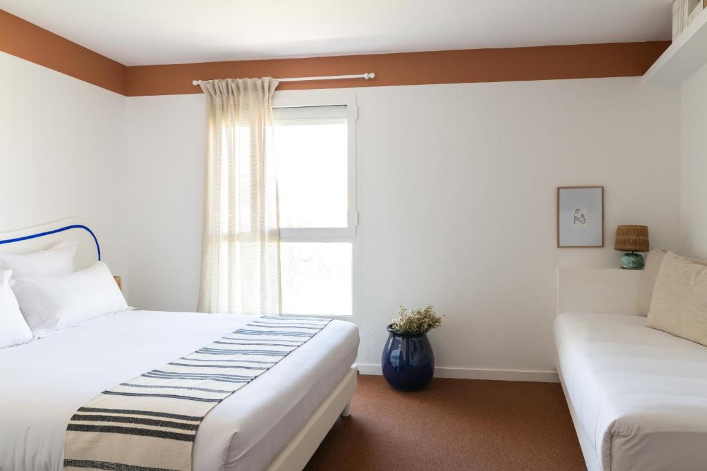 a bedroom with two beds and a window at Hôtel Le Sud in Juan-les-Pins