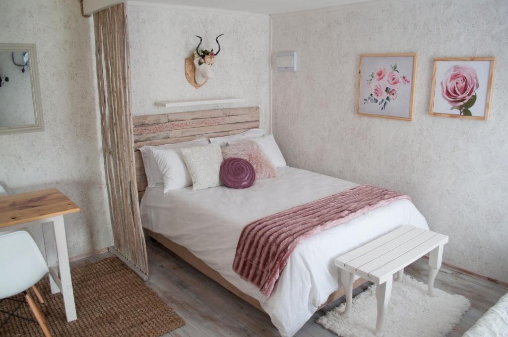 1 dormitorio con cama blanca y mesa de madera en Brakvlei, en Albertinia