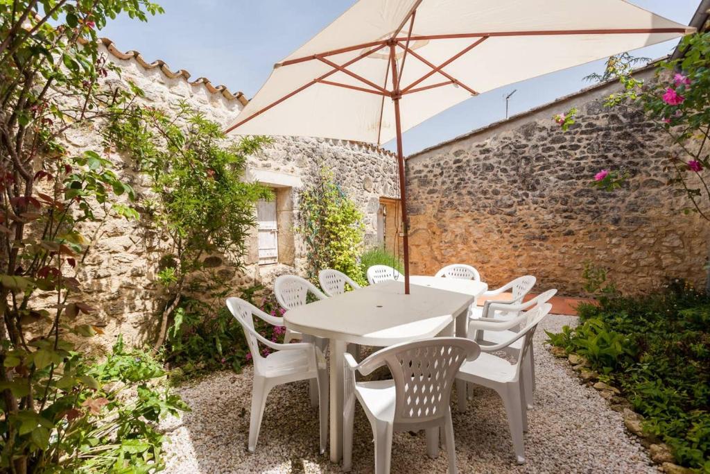 uma mesa branca e cadeiras com um guarda-sol em Villa de 4 chambres avec piscine privee jardin amenage et wifi a Genissac em Génissac