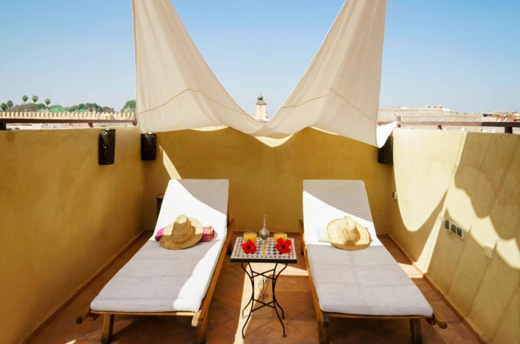 a balcony with two chairs and a table with fruit at 6 bedrooms villa with private pool jacuzzi and furnished terrace at Marrakech in Marrakesh