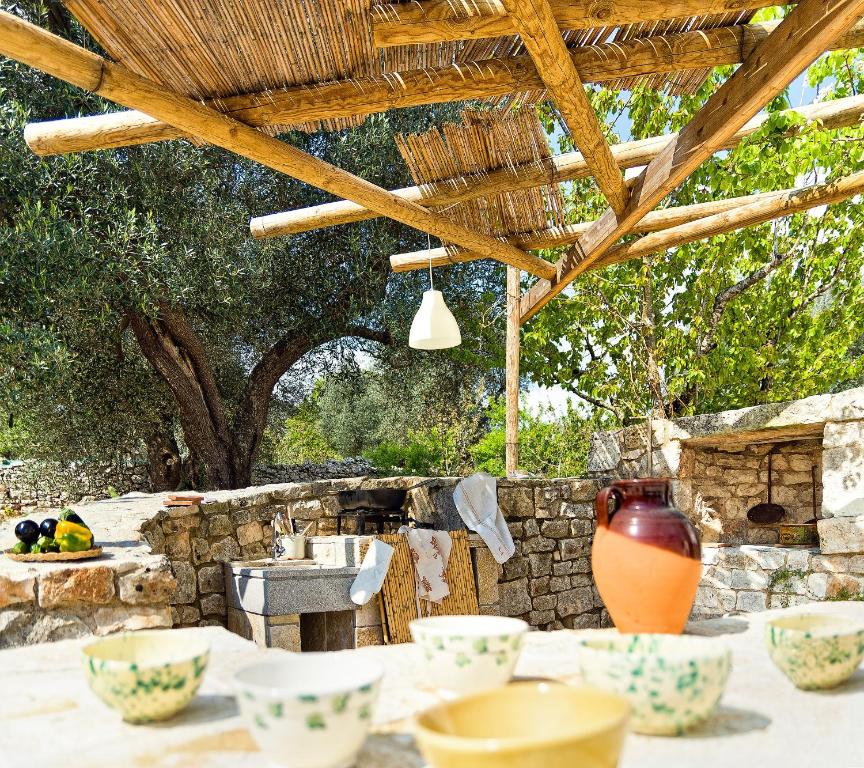 una mesa con tazones bajo un techo de madera en One bedroom house with private pool and furnished garden at Ceglie Messapica, en Ceglie Messapica