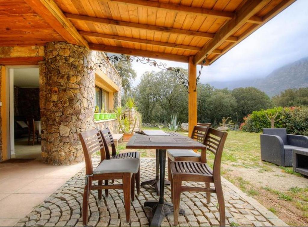 un patio con mesa y sillas bajo un techo de madera en Studio avec jardin amenage et wifi a Moltifao, en Moltifao