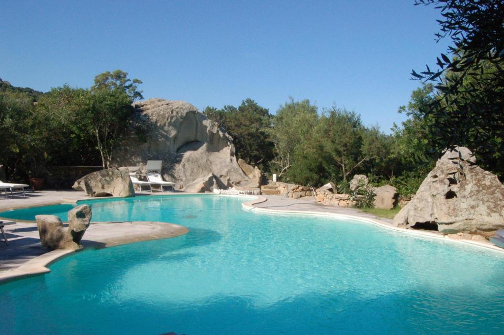 a large swimming pool with blue water and rocks at Modern Villa in Olbia with Shared Pool - 45 sqm in Porto Rotondo