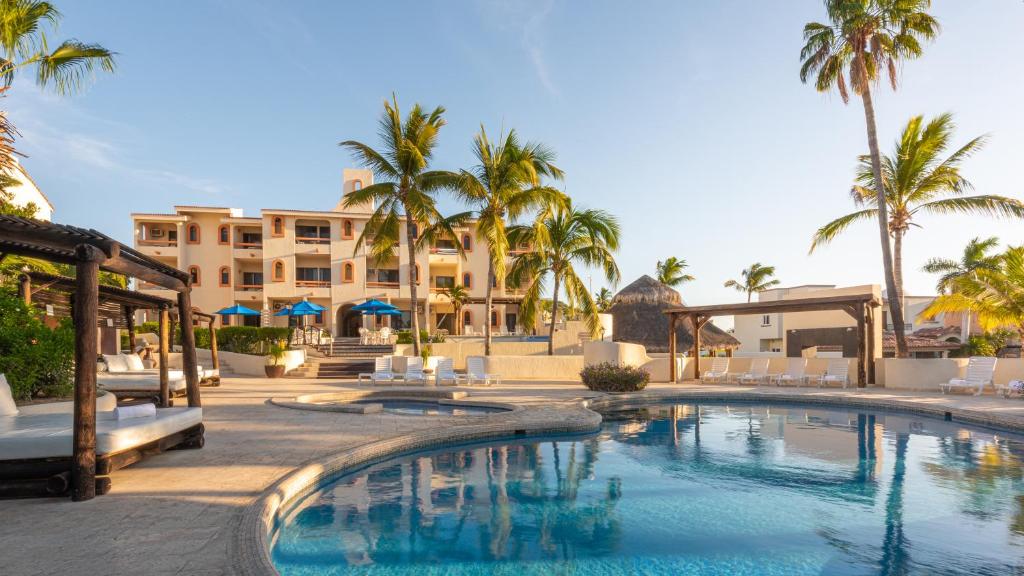 a swimming pool in front of a resort with palm trees at Park Royal Homestay Los Cabos in San José del Cabo