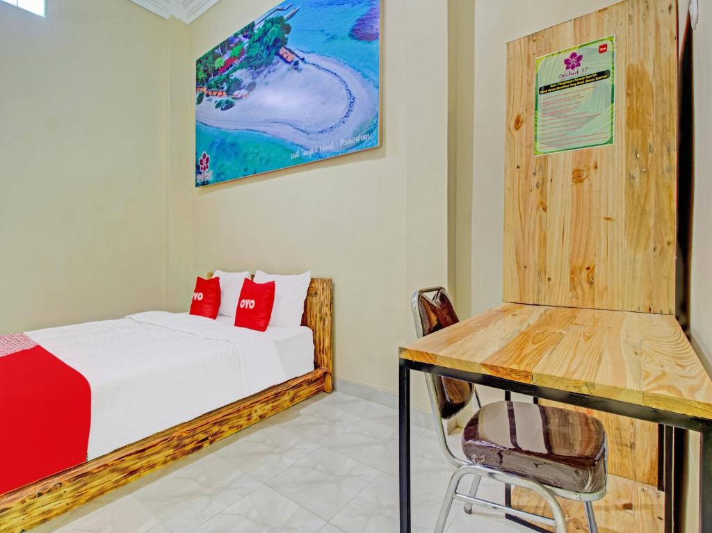 a bedroom with a bed and a desk and a chair at Super OYO 3774 Orchid 37 Syariah Guest House in Bandar Lampung