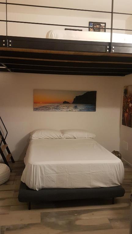 1 dormitorio con 1 cama blanca y una pintura en la pared en La casa a due passi dal mare en Marettimo