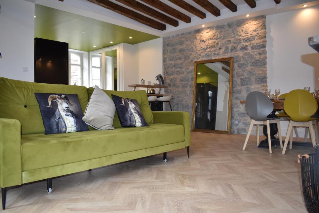 a green couch in a living room with a table at Maison 1747 - Gîtes de Standing en Vieille-ville avec Cour in Boulogne-sur-Mer