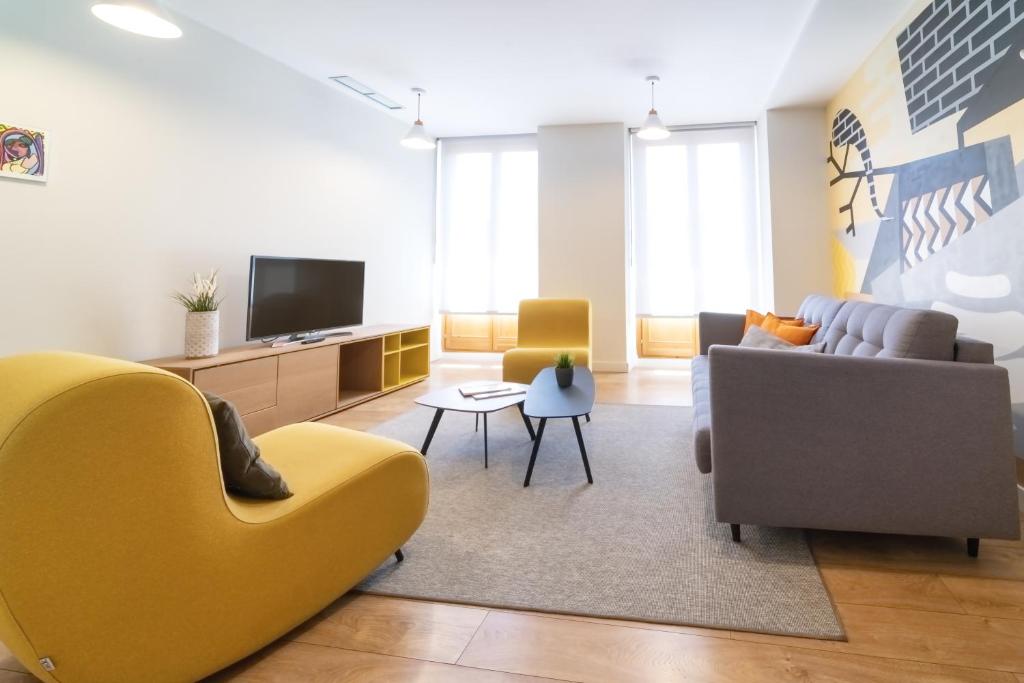 Morar Apartments Malasaña في مدريد: غرفة معيشة مع أريكة وتلفزيون