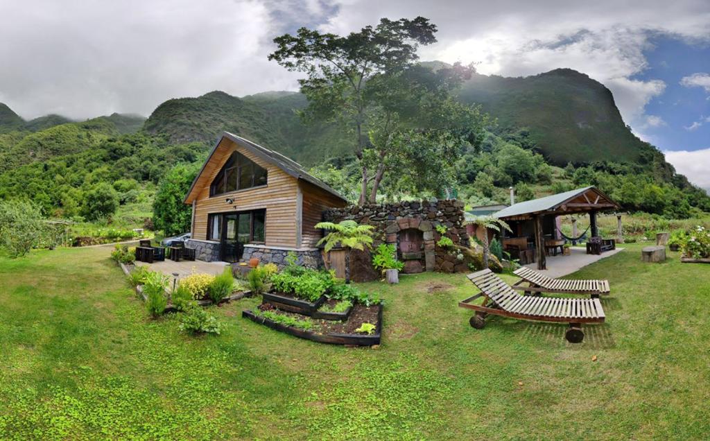 une maison avec bancs dans une cour avec montagnes en arrière-plan dans l'établissement Chale Jardim De Cima, à São Vicente