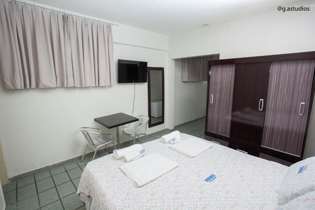 a room with a bed and a table and a tv at HOTEL ZURIQUE in Patos