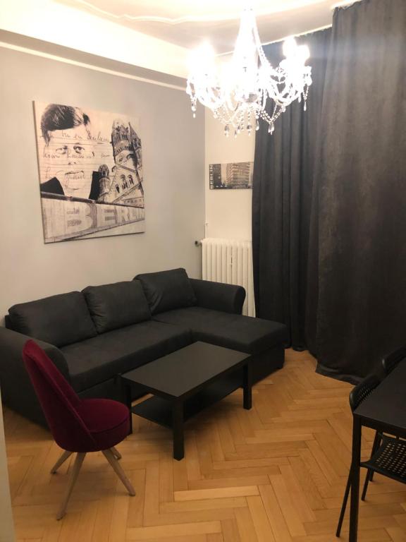 a living room with a black couch and a chandelier at WM- Touristik- Berlin in Berlin