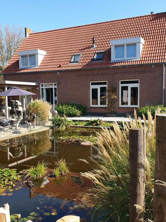 a brick house with a pond in front of it at Het Pauwtje in Zoutelande