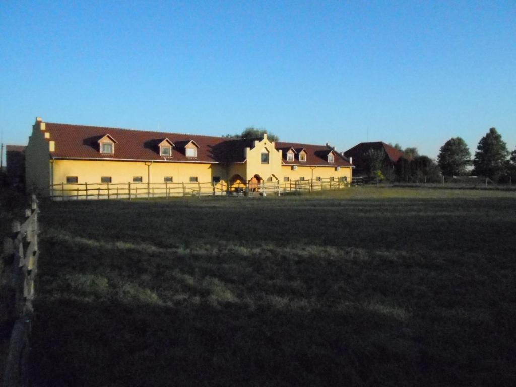 una grande casa con una recinzione di fronte a un campo di Torony Lovarda Magánszállás a Kiskunfélegyháza