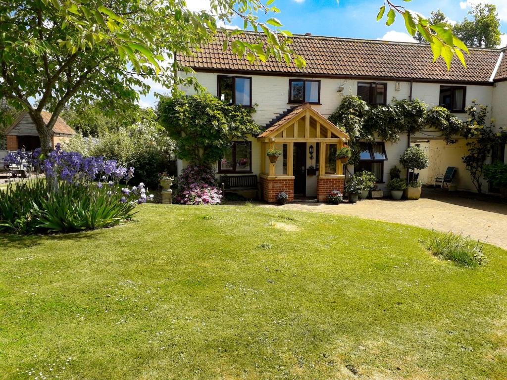 een huis met een groen gazon ervoor bij Berrys Place Farm Cottage in Gloucester