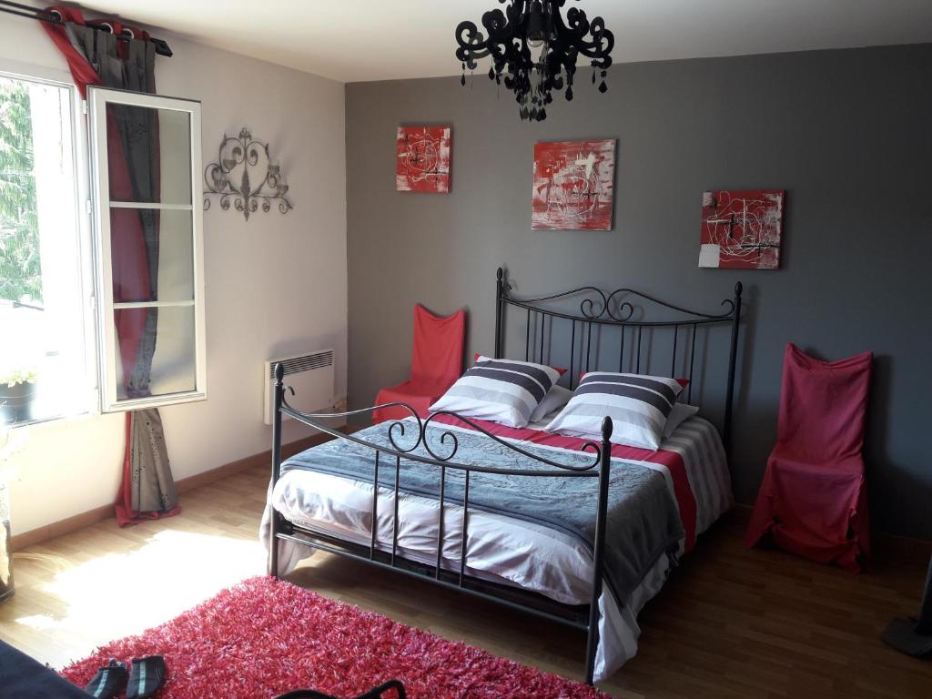 - une chambre avec un lit doté d'oreillers rouges et d'un lustre dans l'établissement appartement complet 11 la roche racan 37370, à Saint-Paterne-Racan