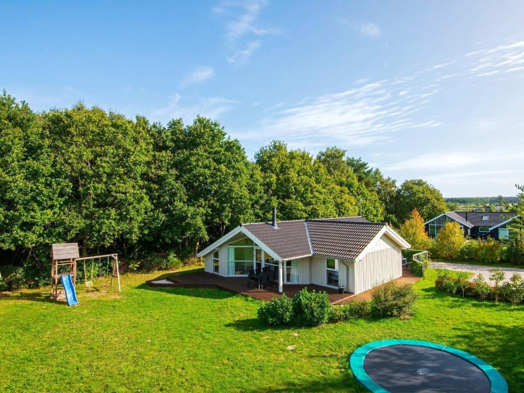 a small house in a yard with a playground at Three-Bedroom Holiday home in Glesborg 28 in Fjellerup Strand