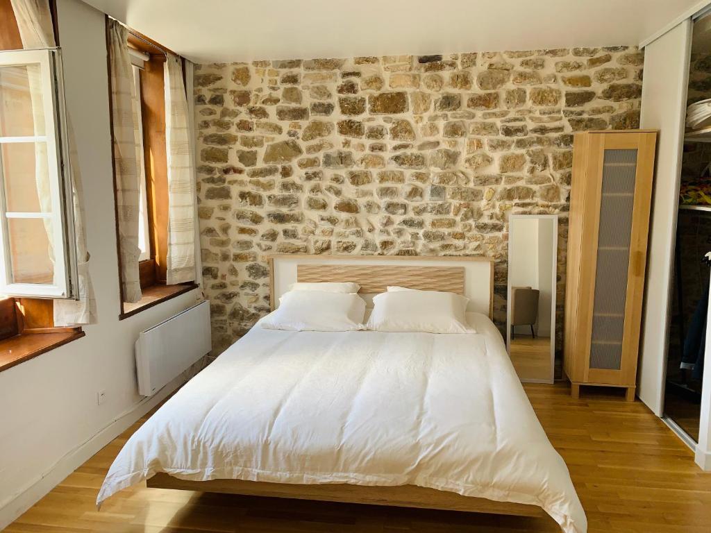 una camera da letto con un grande letto bianco e un muro in pietra di Le cottage des remparts - face hotel de ville a Boulogne-sur-Mer