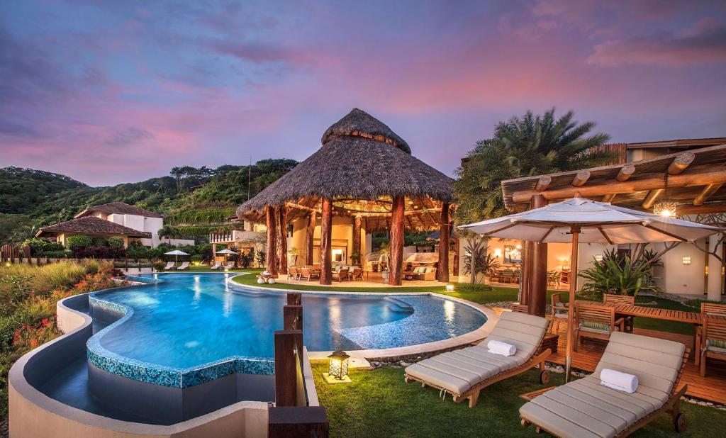 an outdoor swimming pool with a gazebo at Mukul Resort in Tola