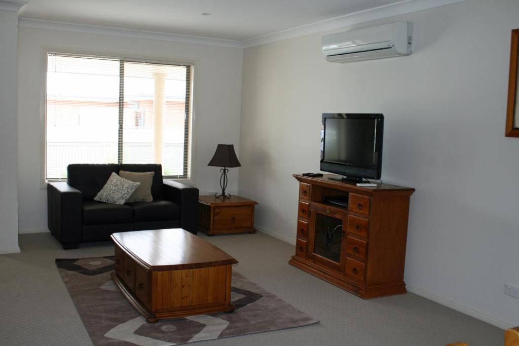 sala de estar con TV, sofá y mesa de centro en Breakaway Apartments, en Cowra