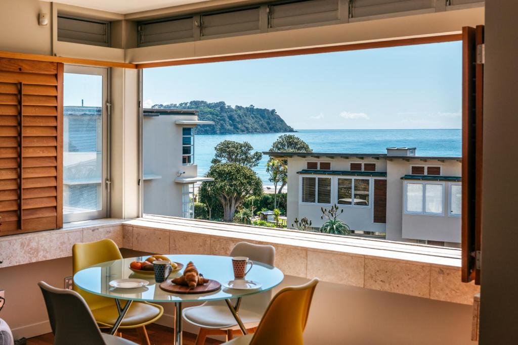 a room with a table and chairs and a large window at Sanctuary On The Beach - Onetangi by Waiheke Unlimited in Onetangi