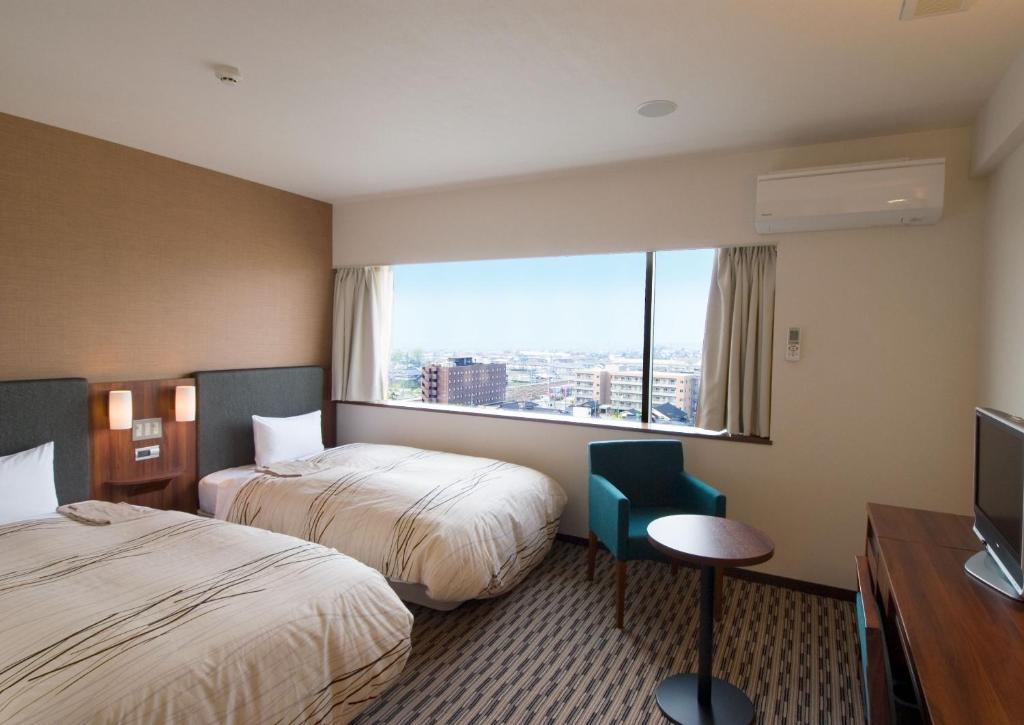 een hotelkamer met 2 bedden en een raam bij Uozu Manten Hotel Ekimae in Uozu