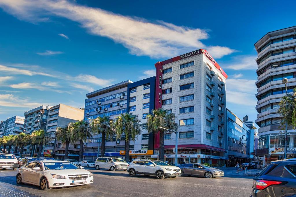 un estacionamiento con autos estacionados frente a un edificio en Kozan City Hotel en İzmir