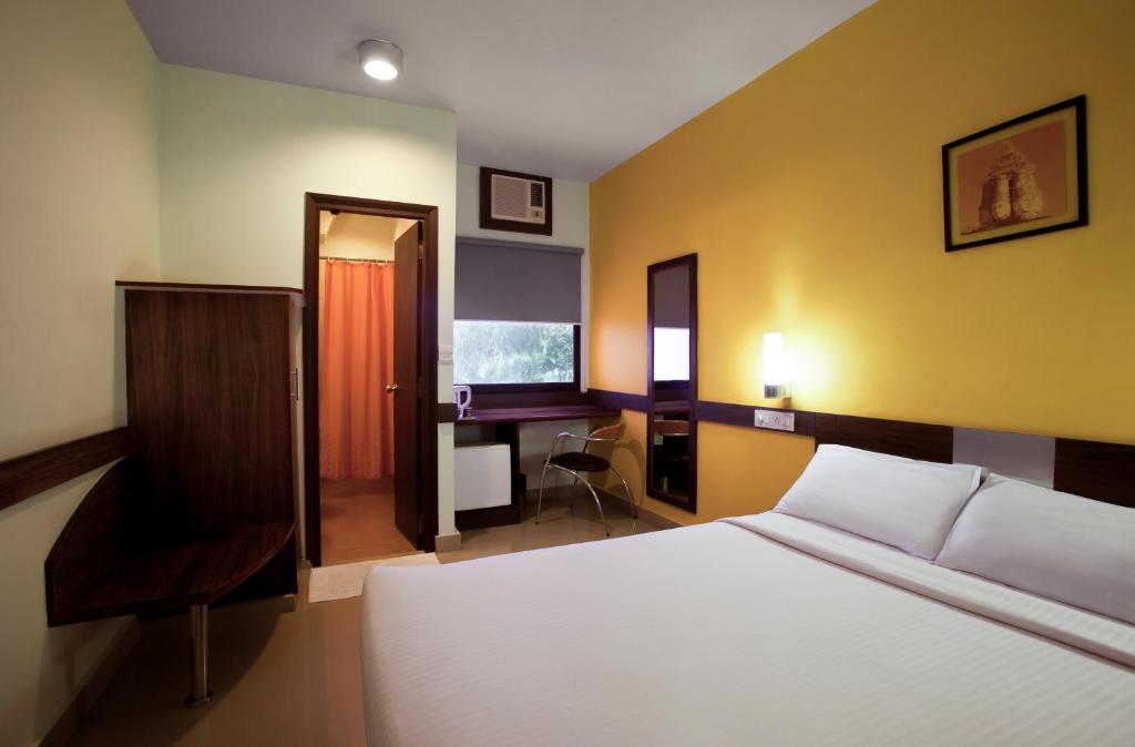 a bedroom with a bed and a desk and a chair at Ginger Guwahati in Guwahati