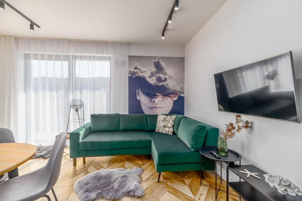 ein Wohnzimmer mit einem grünen Sofa und einem Fernseher in der Unterkunft Stylish Apartment Balticus 15 with Air Conditioning by Noclegi Renters in Misdroy