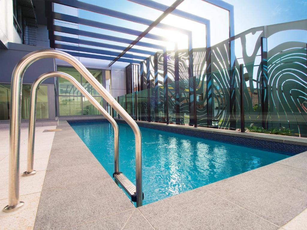 a swimming pool in a building with metal hand rails at Oaks Gladstone Grand Hotel in Gladstone