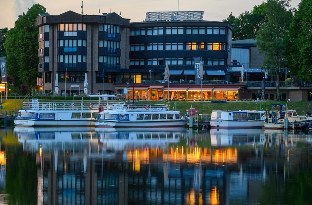 a building with boats in the water in front of a building at Hotel am Wasserfall in Lingen