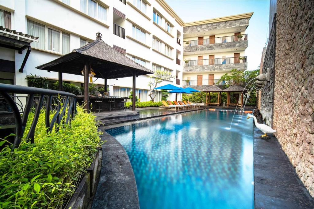 a swimming pool in front of a building at Natya Hotel Kuta in Kuta