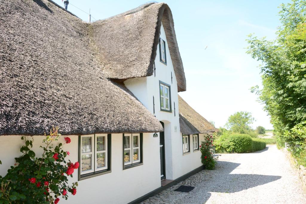 a cottage with a thatched roof and a pathway at FÖHRIENHAUS stilvolle 5 Sterne Einheiten in ruhiger Marschrandlage auf Föhr für Gäste, die das Besondere schätzen, gerne auch mit Hund in Midlum