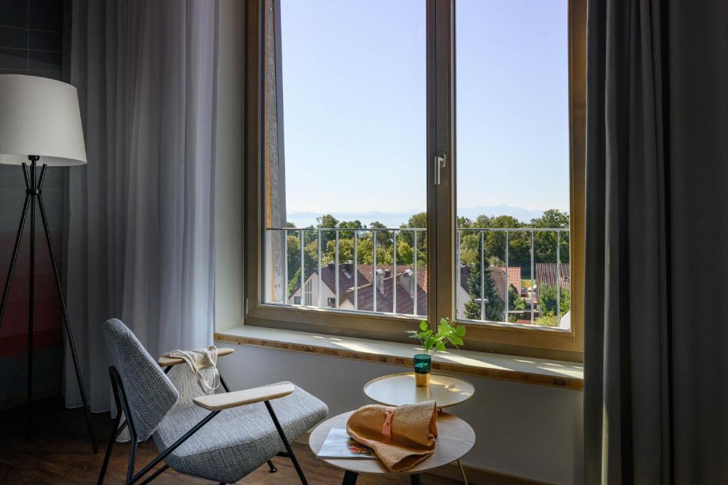 Zimmer mit einem großen Fenster mit 2 Stühlen und einem Tisch in der Unterkunft Hotel Maier in Friedrichshafen