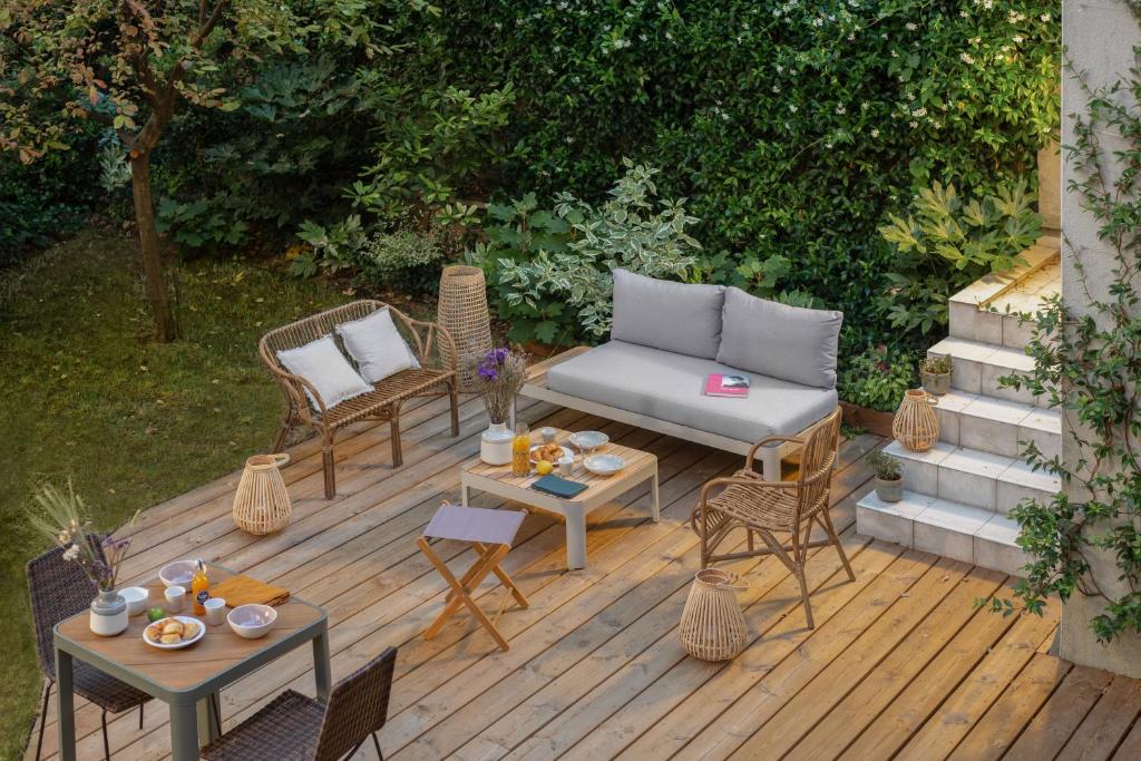 een houten terras met stoelen, een bank en tafels bij PEPPER & PAPER Apartments in Parijs