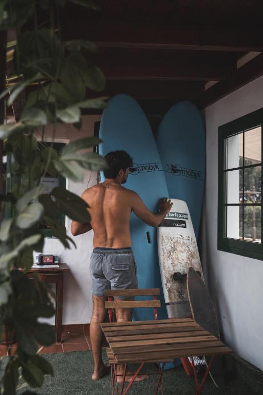 a man is holding a surfboard in a room at Surfescape Fuerteventura in Lajares