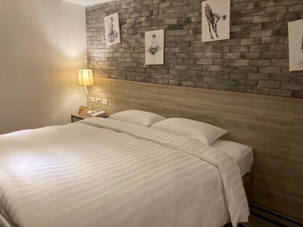 a bedroom with a white bed and a brick wall at RF Hotel - Zhongxiao in Taipei