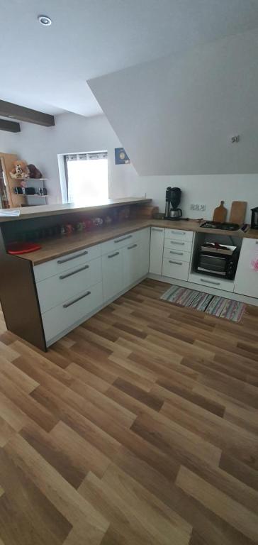 a kitchen with white cabinets and a wooden floor at Nocleg U Jagódki in Zubrzyca Dolna