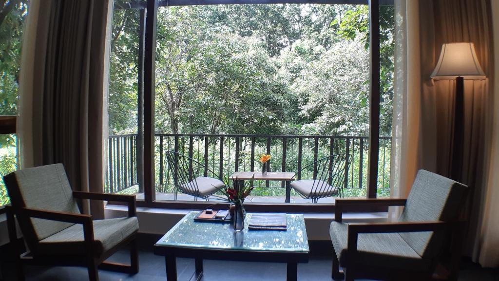 a room with a table and chairs and a large window at Saraca Resort & Spa Corbett in Garjia